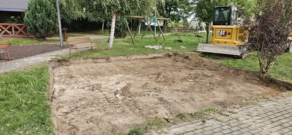 Koparka CAT przy wybranej i wyrównanej powierzchni placu zabaw
